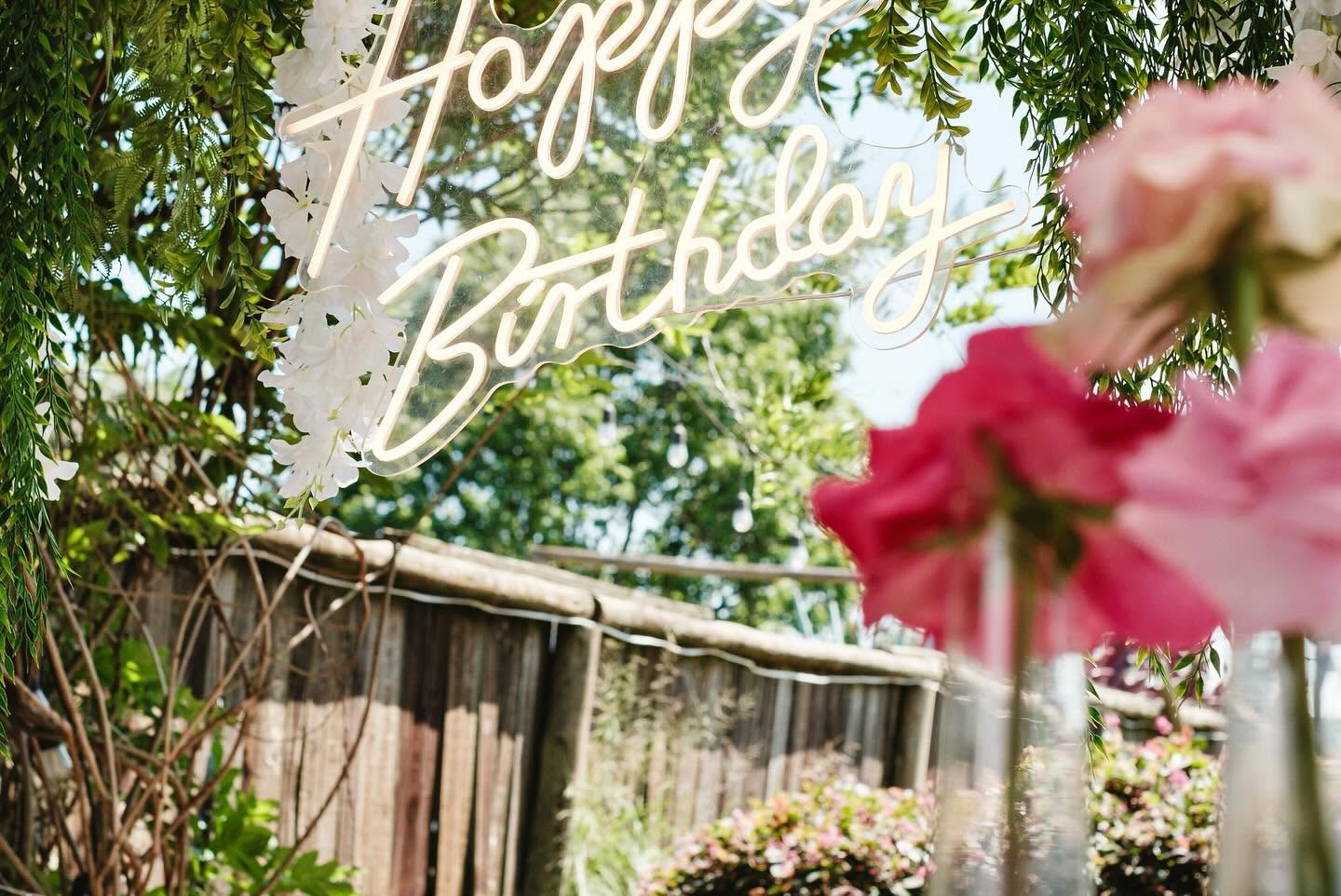 Neon birthday sign among garden foliage