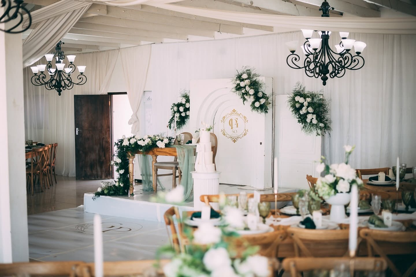 Indoor hall with chandeliers, white draping and greenery