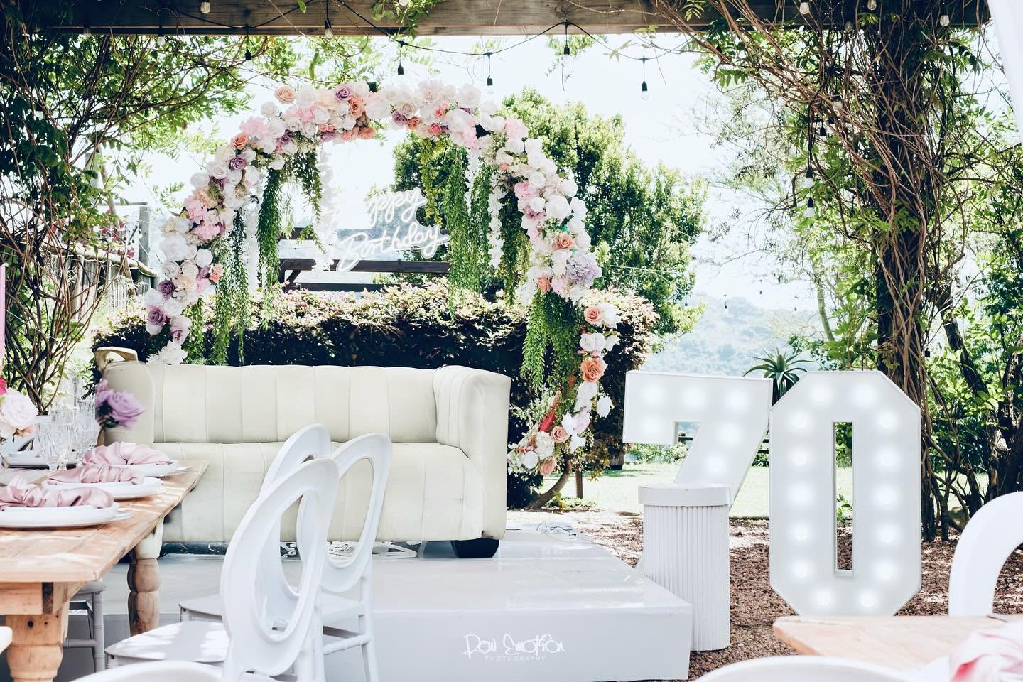 Birthday lounge with a floral arch and illuminated numbers