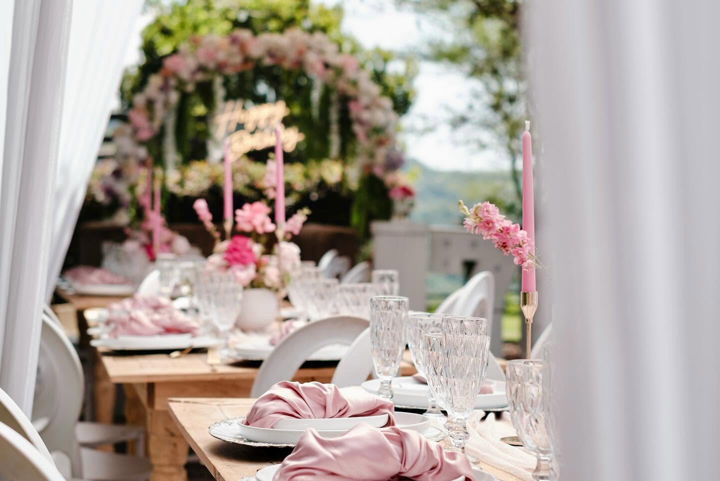 Blush table setting with tapered candles under a draped canopy