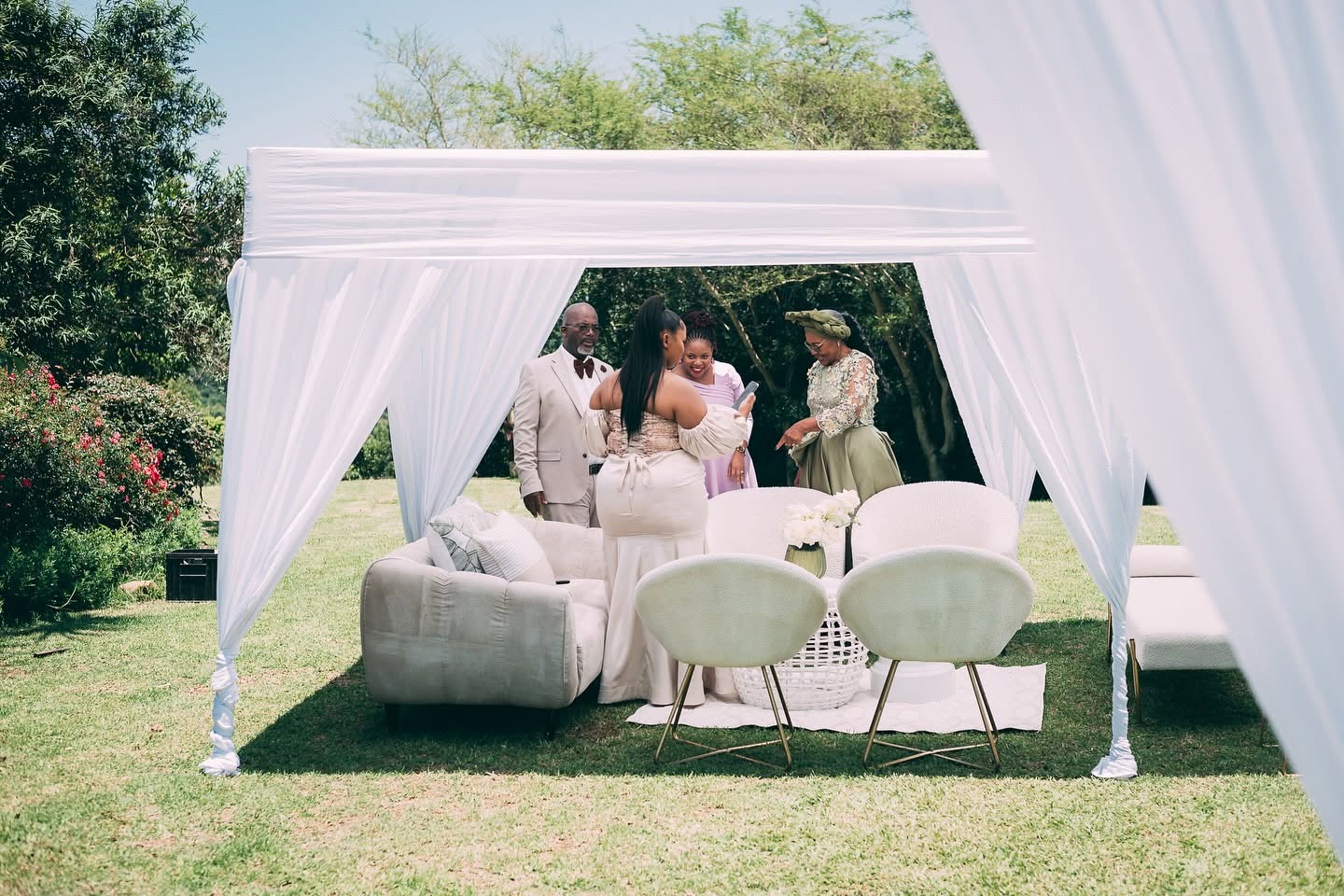 Guests in a white draped cabana lounge on the lawn